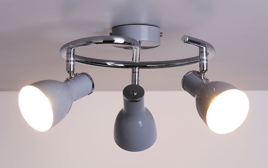 Plafonnier allumé, trois spots diffusant une lumière chaude vers le bas