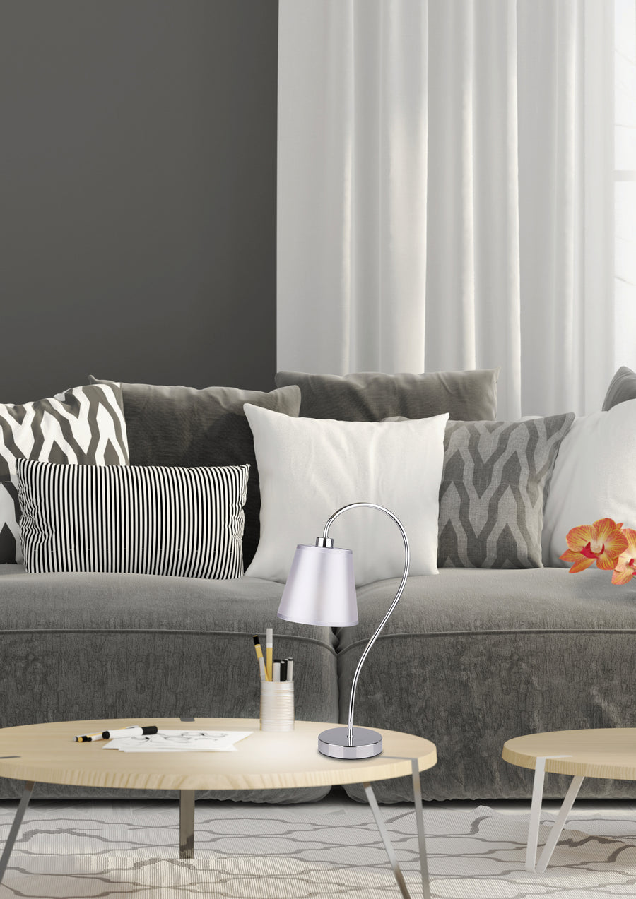 Lampe posée sur table basse, canapé gris et coussins en arrière-plan.