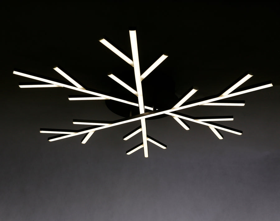 Le luminaire noir brille dans l'obscurité, montrant ses branches LED blanches rayonnantes.