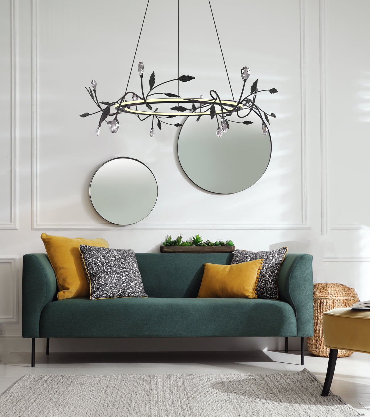 Suspension anneau noir et doré au-dessus d'un canapé vert et miroirs ronds.