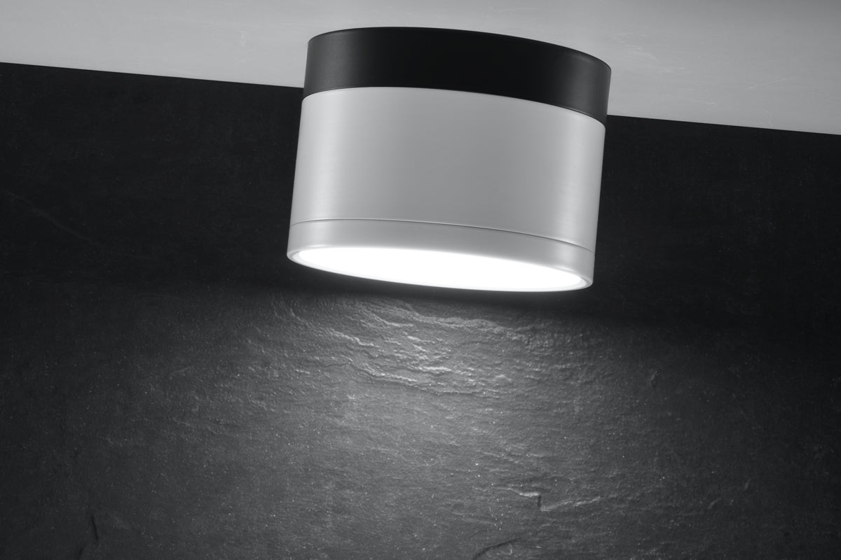 Gros plan du spot cylindrique blanc et noir allumé sur plafond sombre