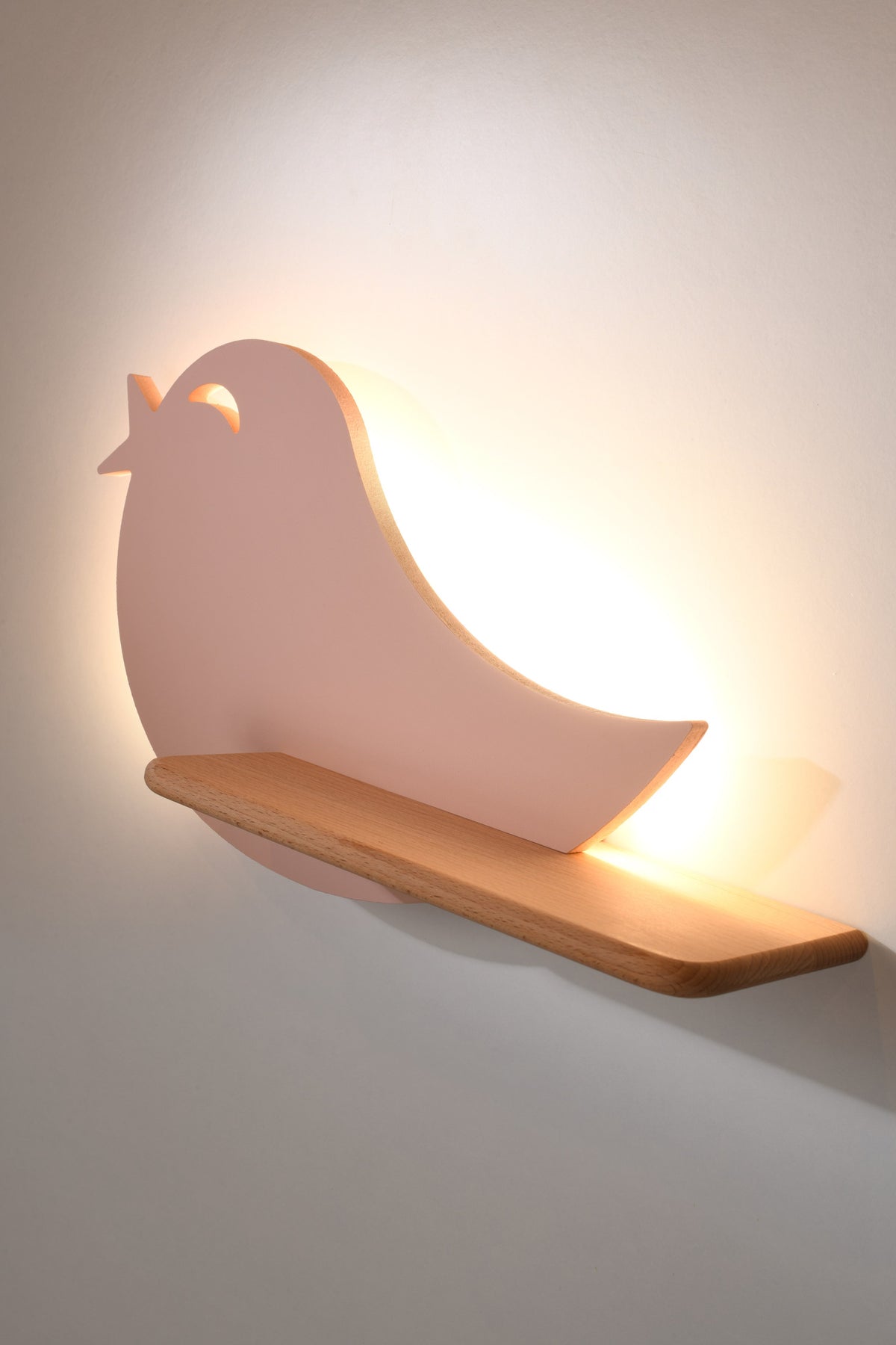 Détail de l'éclairage LED allumé projetant un halo chaud derrière l'oiseau rose