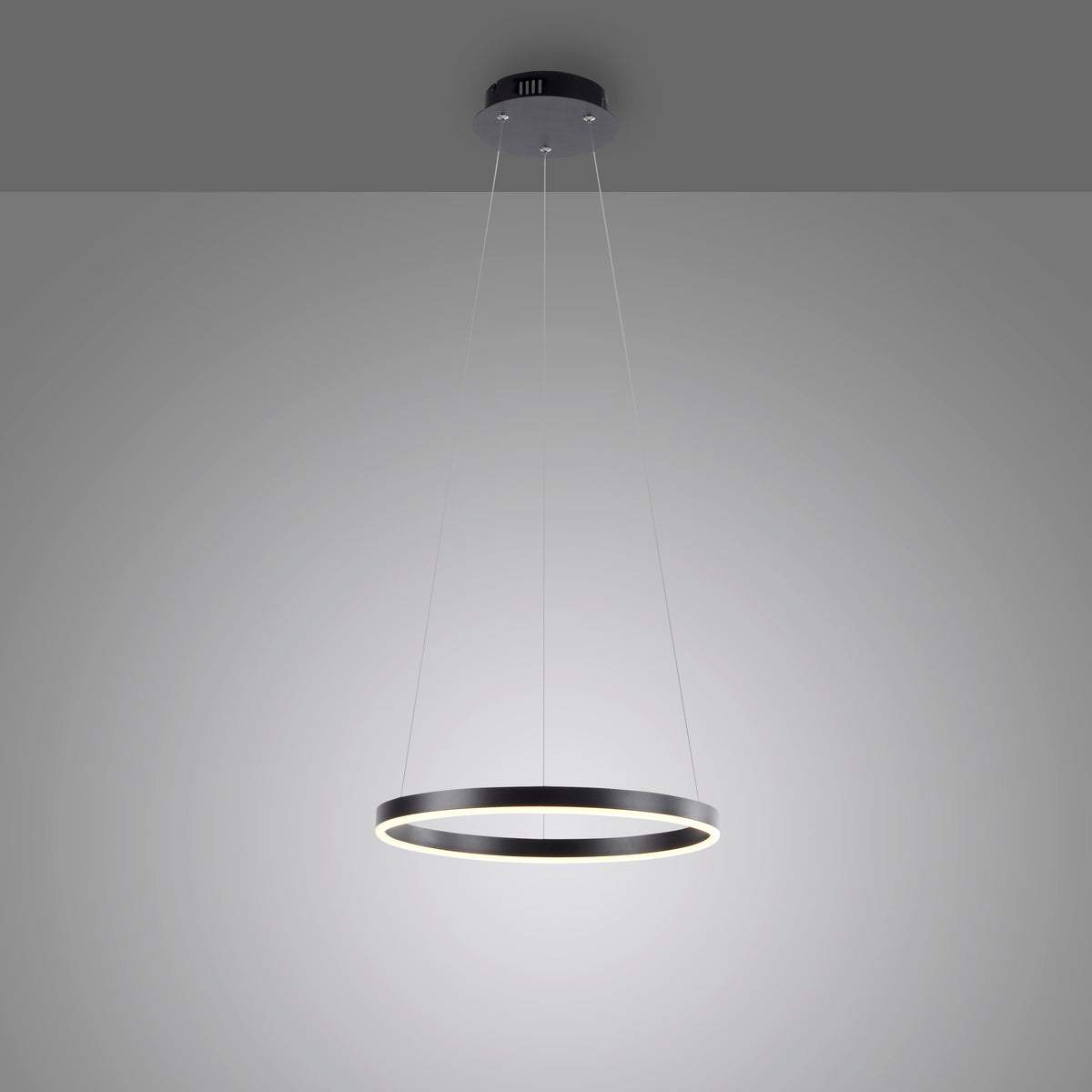 Vue en plongée de la suspension allumée sur fond gris dégradé, mettant en valeur son halo.