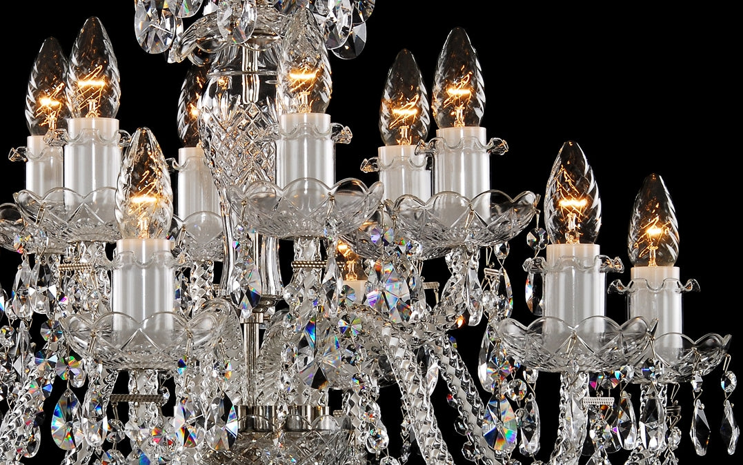 Gros plan sur les bras lumineux, coupelles ciselées et bougies en verre dépoli
