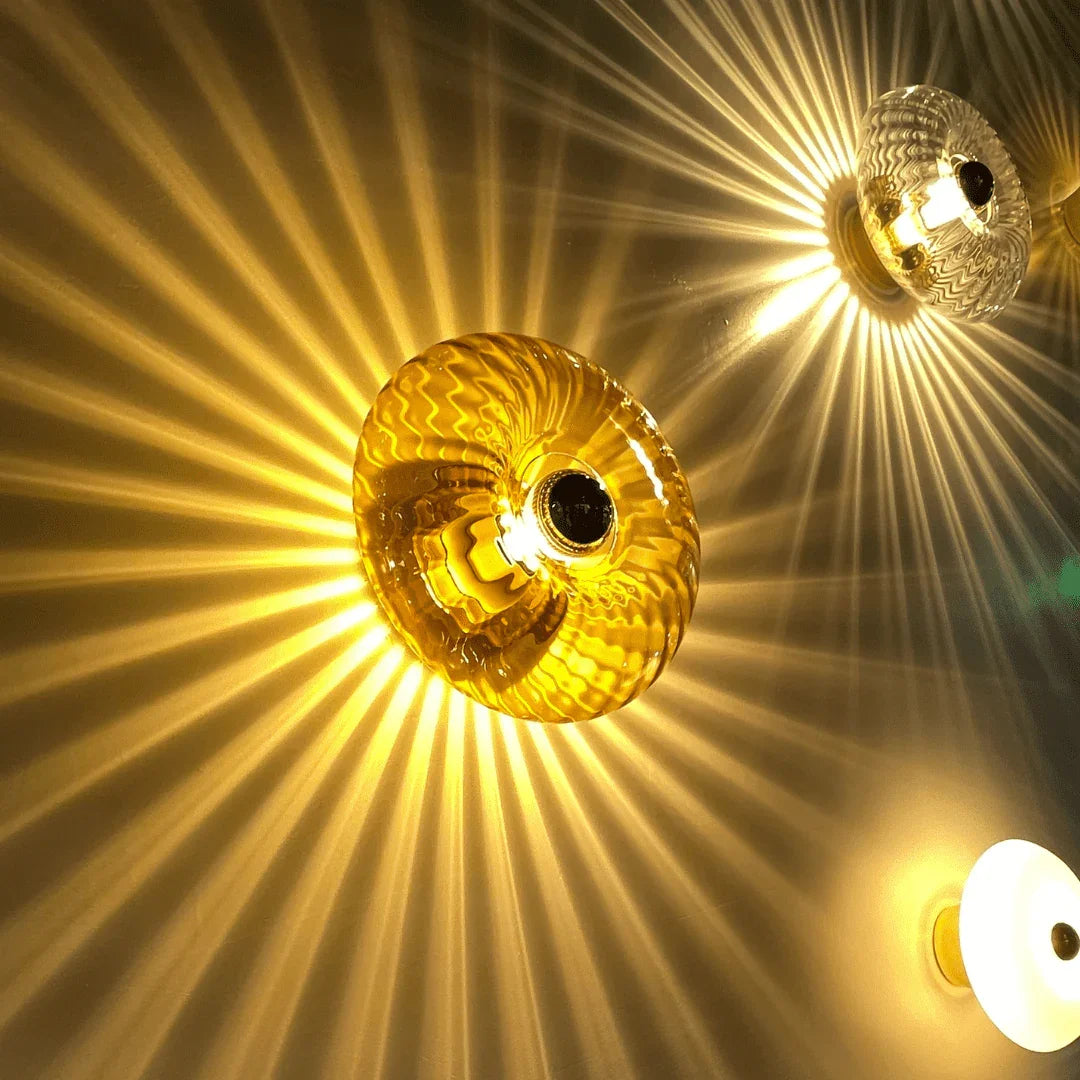 Gros plan sur une applique en verre ambré diffusant une lumière dorée en étoile