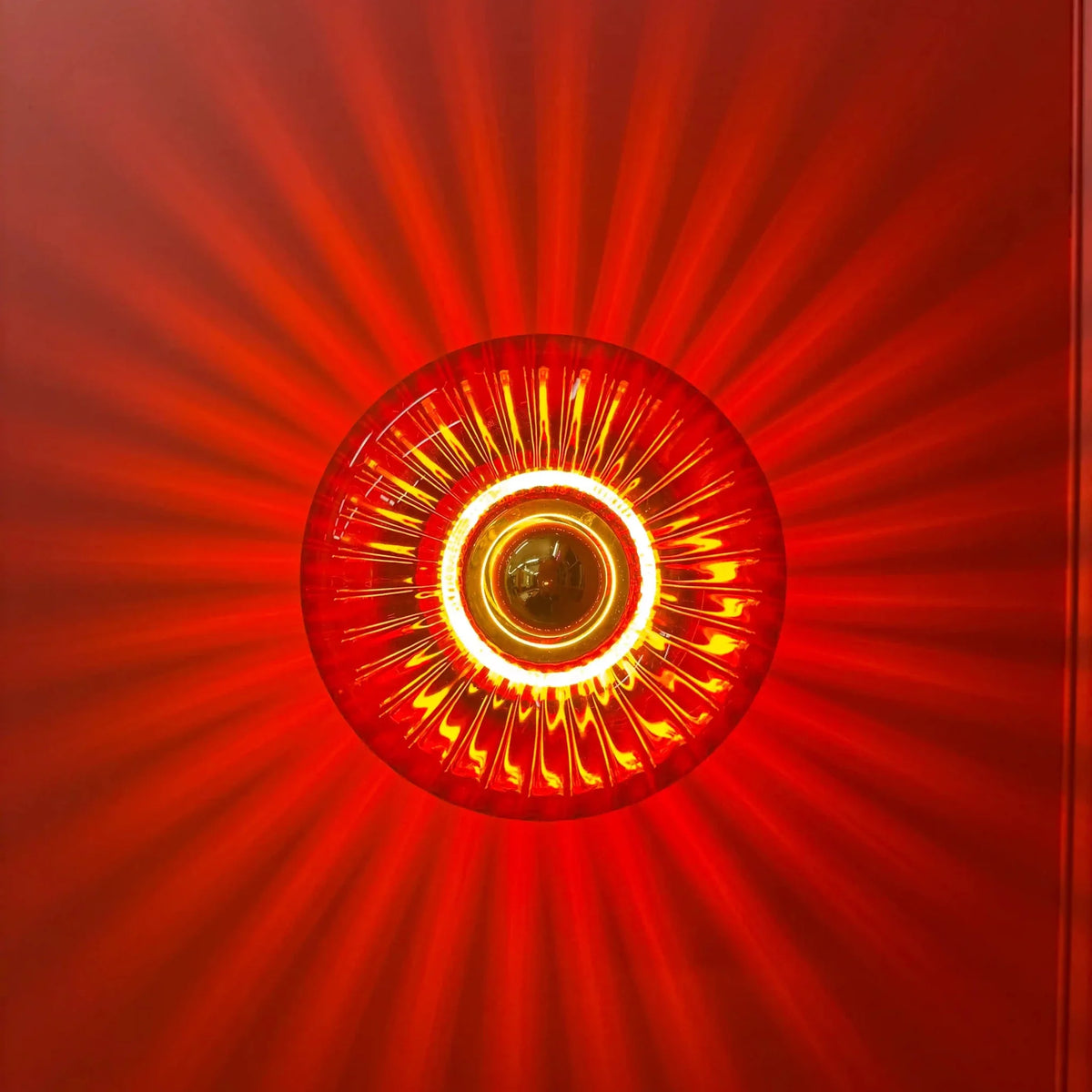 Gros plan du disque de verre rouge diffusant une lumière écarlate en rayons