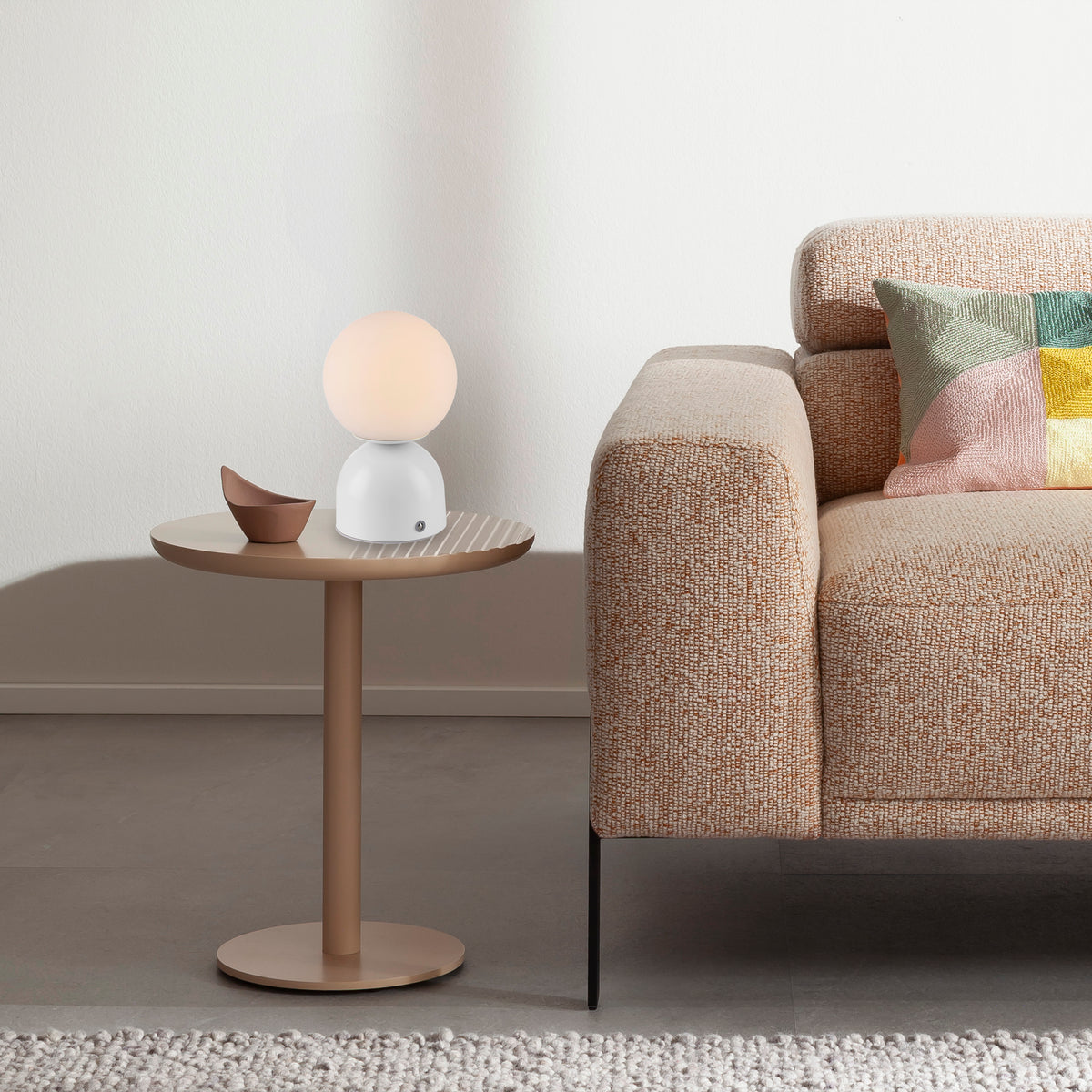 Lampe posée sur table d'appoint à côté d'un canapé, dans un salon chaleureux.