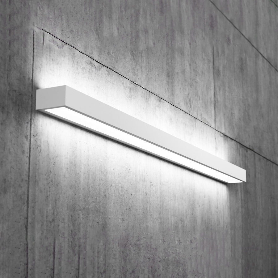 Applique murale LED blanche allumée, fixée sur un mur en béton texturé.