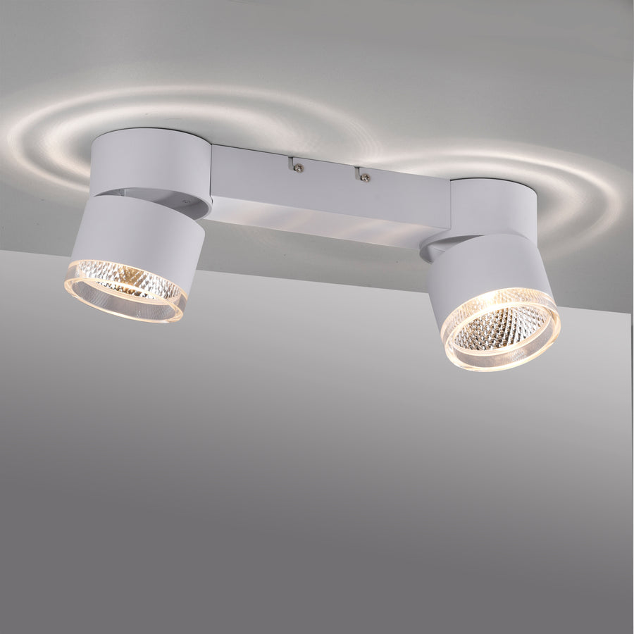 Luminaire allumé au plafond projetant deux halos lumineux circulaires sur la surface blanche