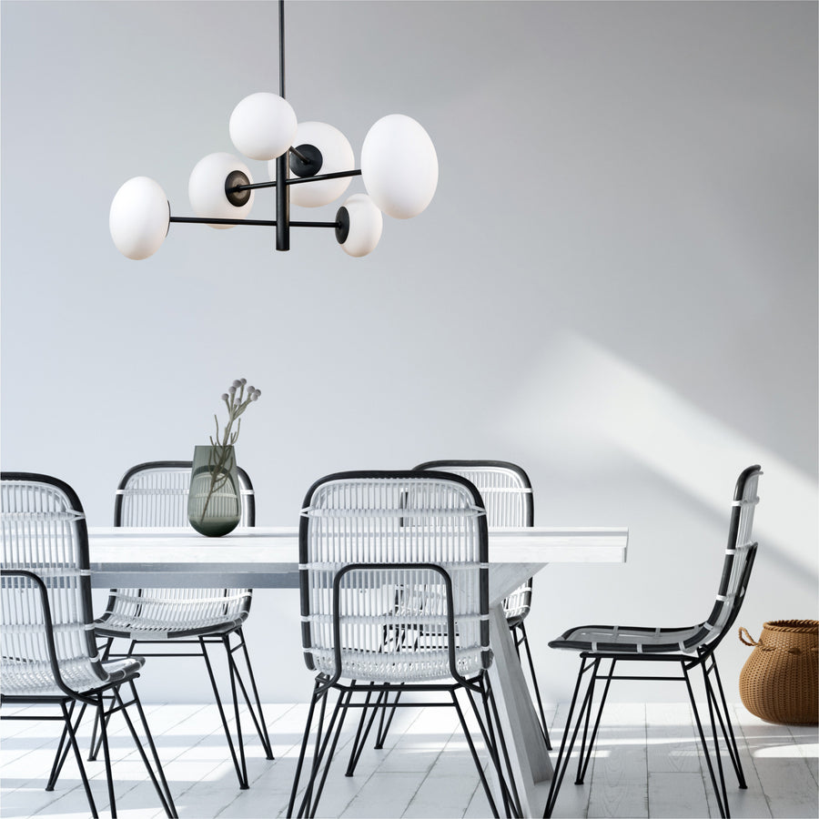 Suspension noire suspendue au-dessus d'une table blanche avec chaises en rotin
