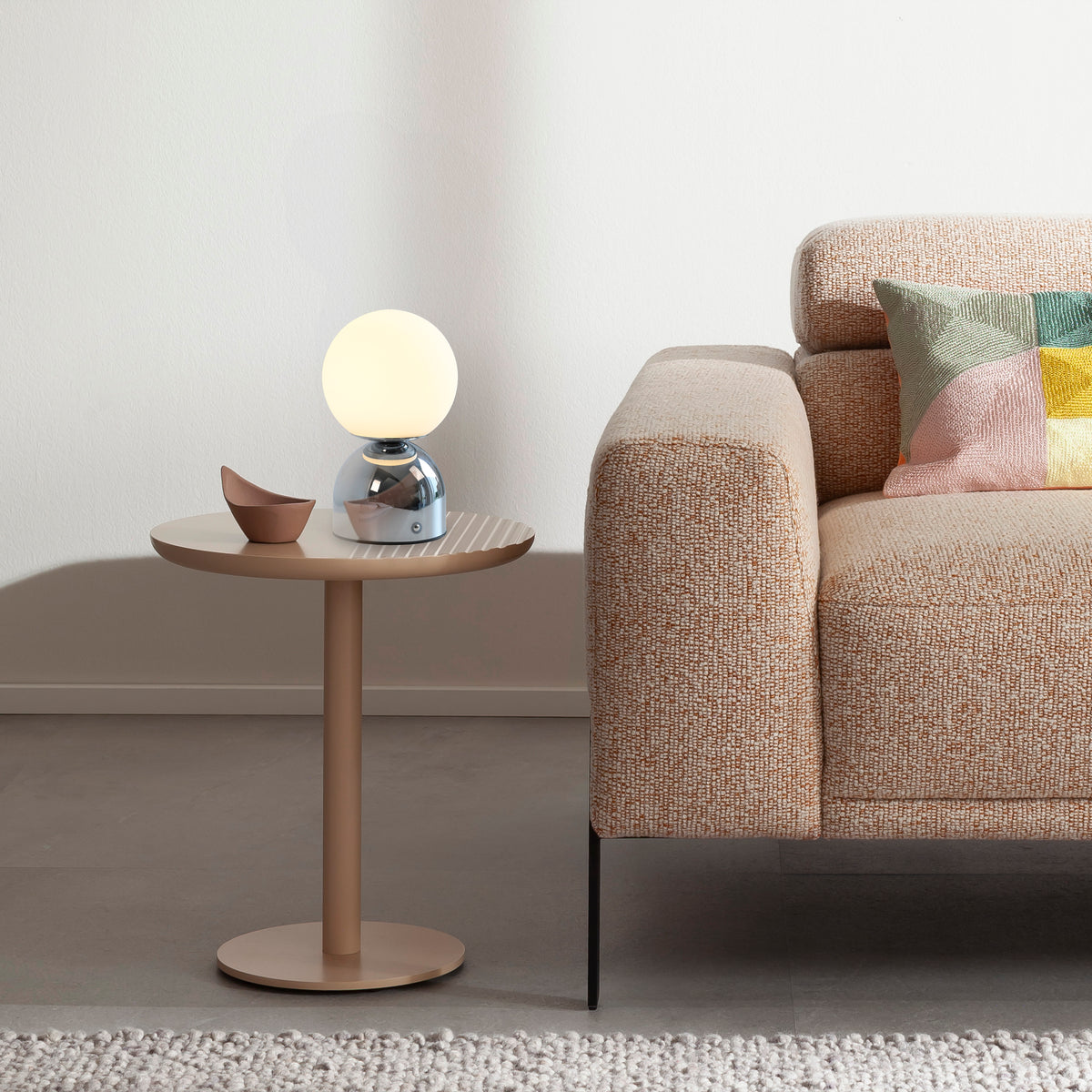 Lampe posée sur table d'appoint devant un canapé beige, ambiance chaleureuse