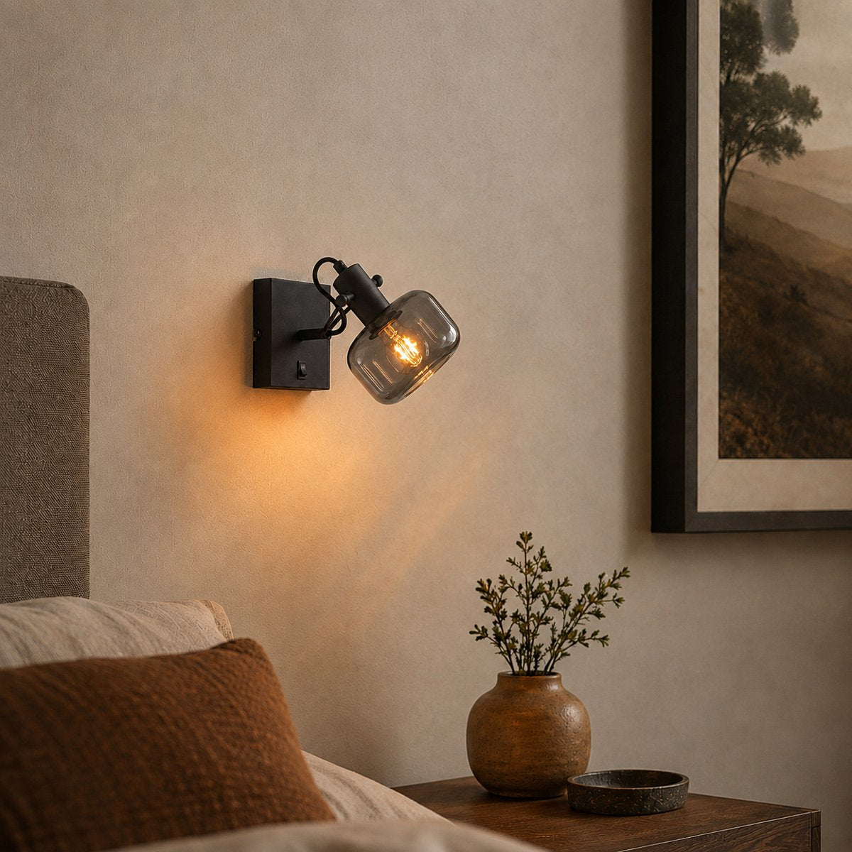 Mise en ambiance chaleureuse au-dessus d'un lit, applique murale noire allumée éclairant la chambre.