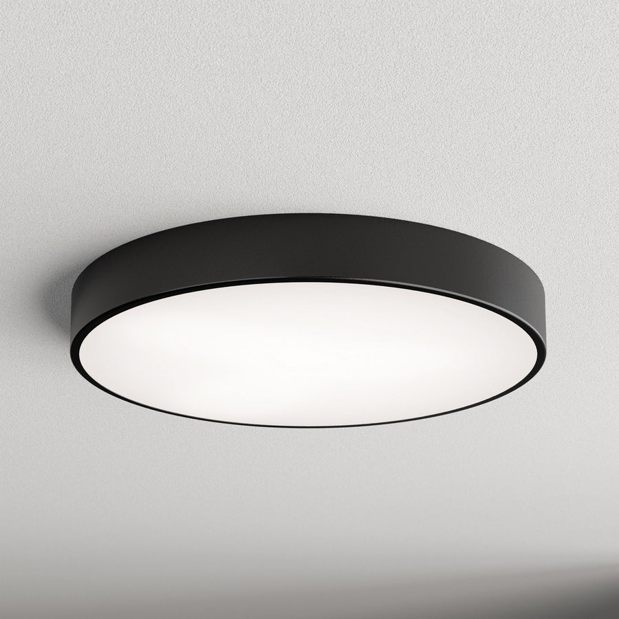 Plafonnier rond noir fixé au plafond, diffuseur blanc lumineux, vue de face.