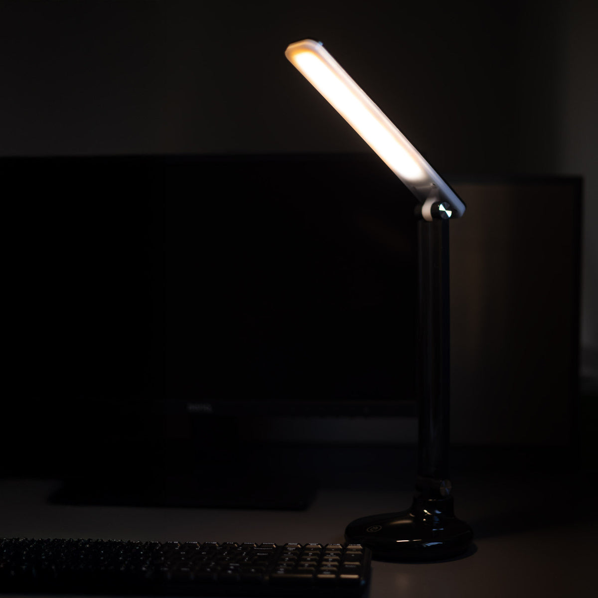 Ambiance de travail nocturne, lampe allumée près d'un clavier et d'un écran