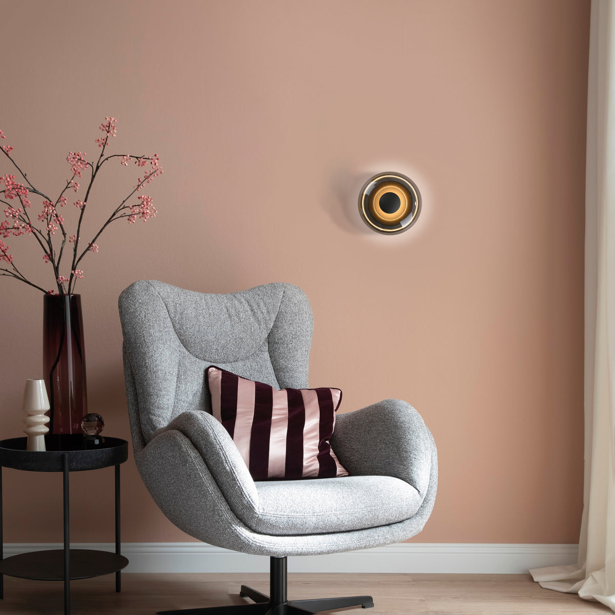 Mise en ambiance dans un salon, fauteuil en tissu gris et mur terracotta poudré