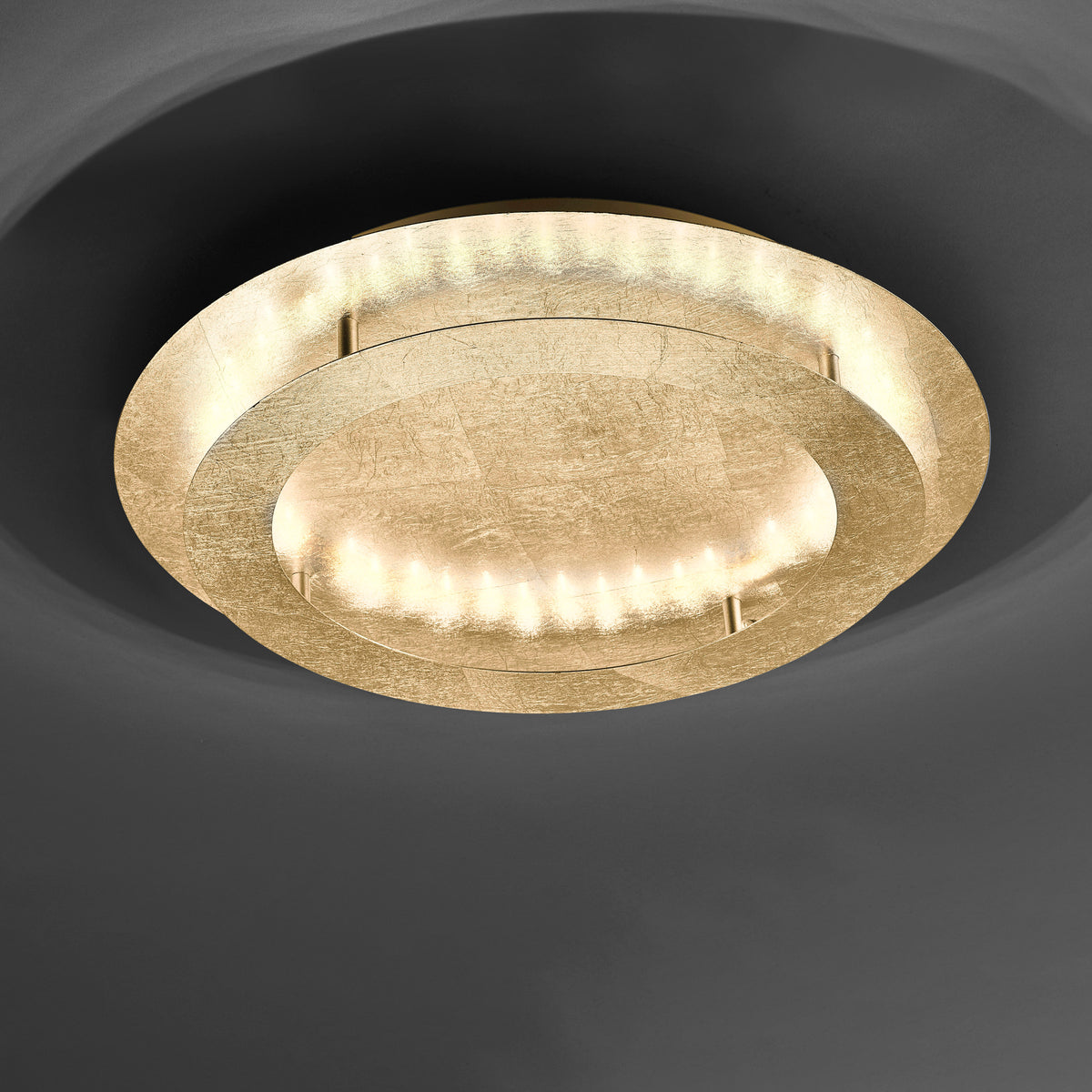 Vue de face du plafonnier doré fixé au plafond sombre, anneau lumineux allumé