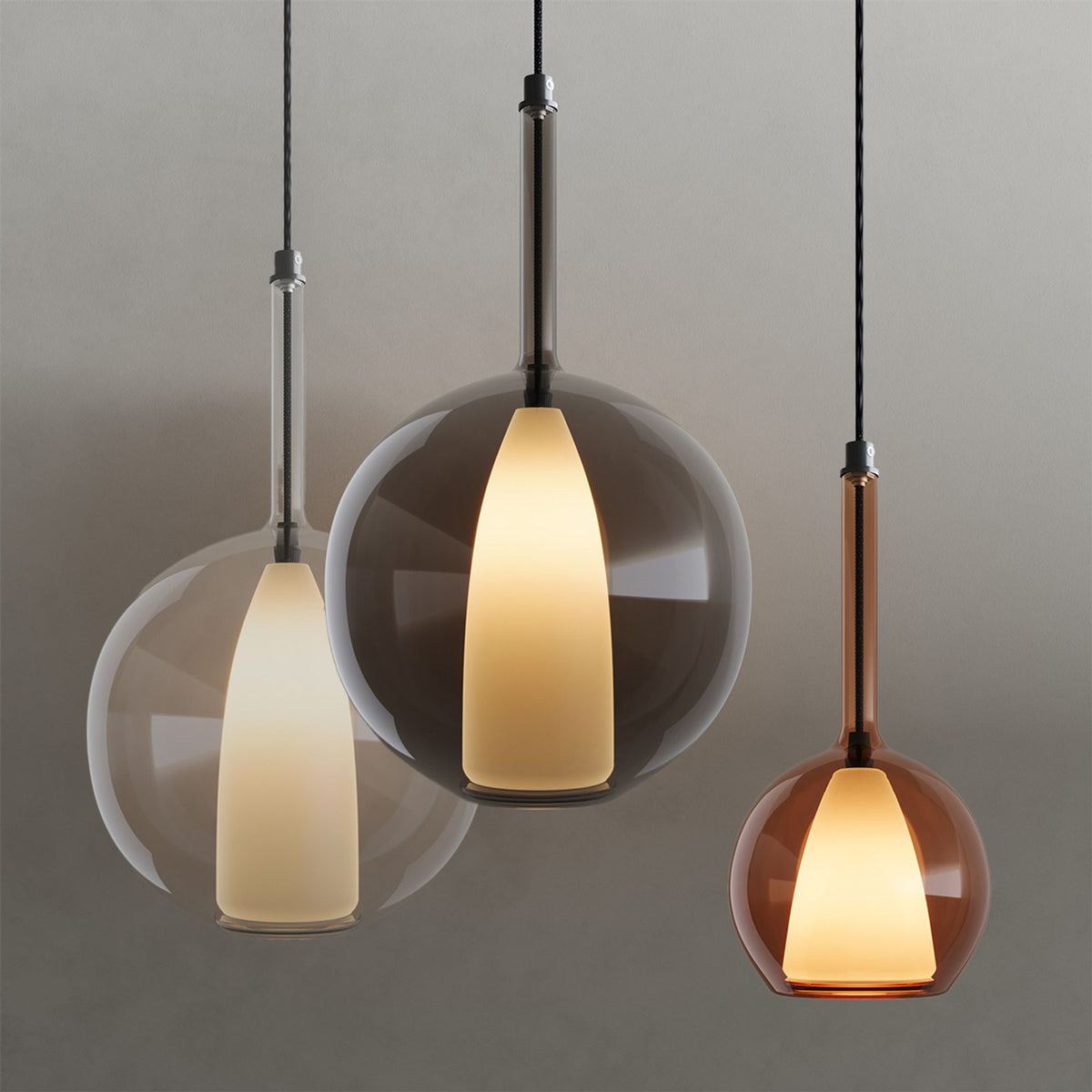 Trois globes de tailles et teintes différentes suspendus sur fond gris neutre