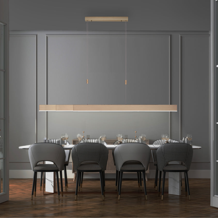 Suspension linéaire éclairant une table à manger dans un intérieur contemporain gris.