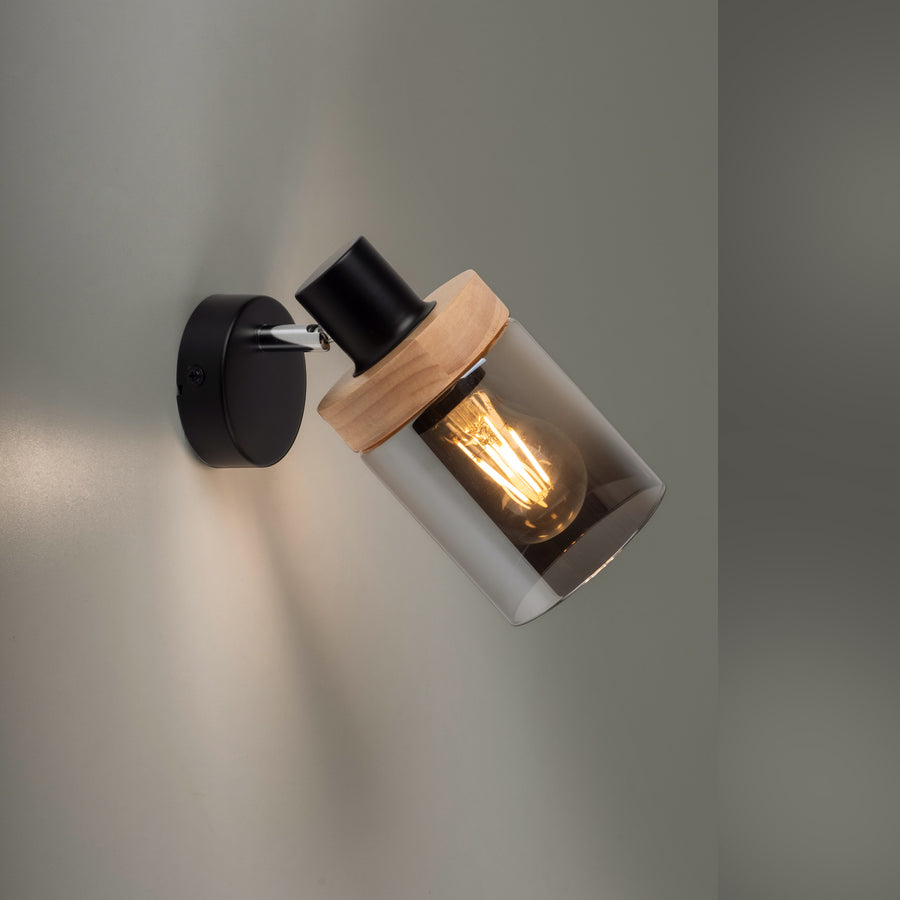 Gros plan du luminaire allumé diffusant une lumière chaude sur un mur gris