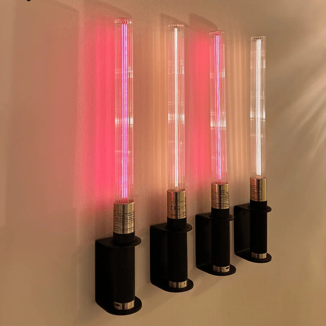 Quatre appliques tubulaires alignées au mur diffusant une lumière rouge rosée