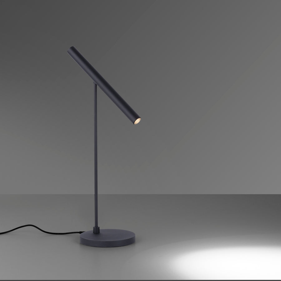Lampe noire sur fond gris, câble visible et éclairage dirigé vers le bas.