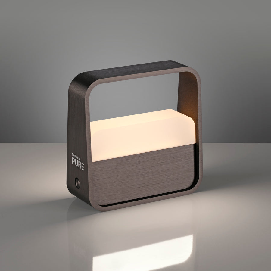 Lampe allumée posée sur surface réfléchissante, ombre portée et lumière chaude.