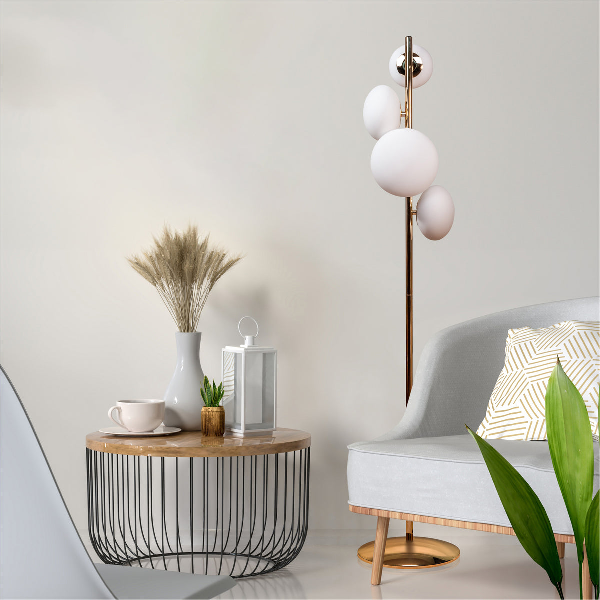 Mise en ambiance : lampadaire allumé près d'un fauteuil gris, table basse et vase à plumes.