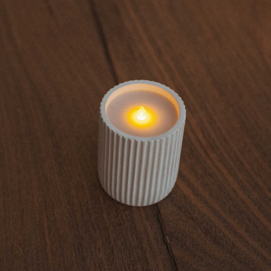 Vue en plongée de la lampe bougie en céramique sur un parquet en bois sombre.