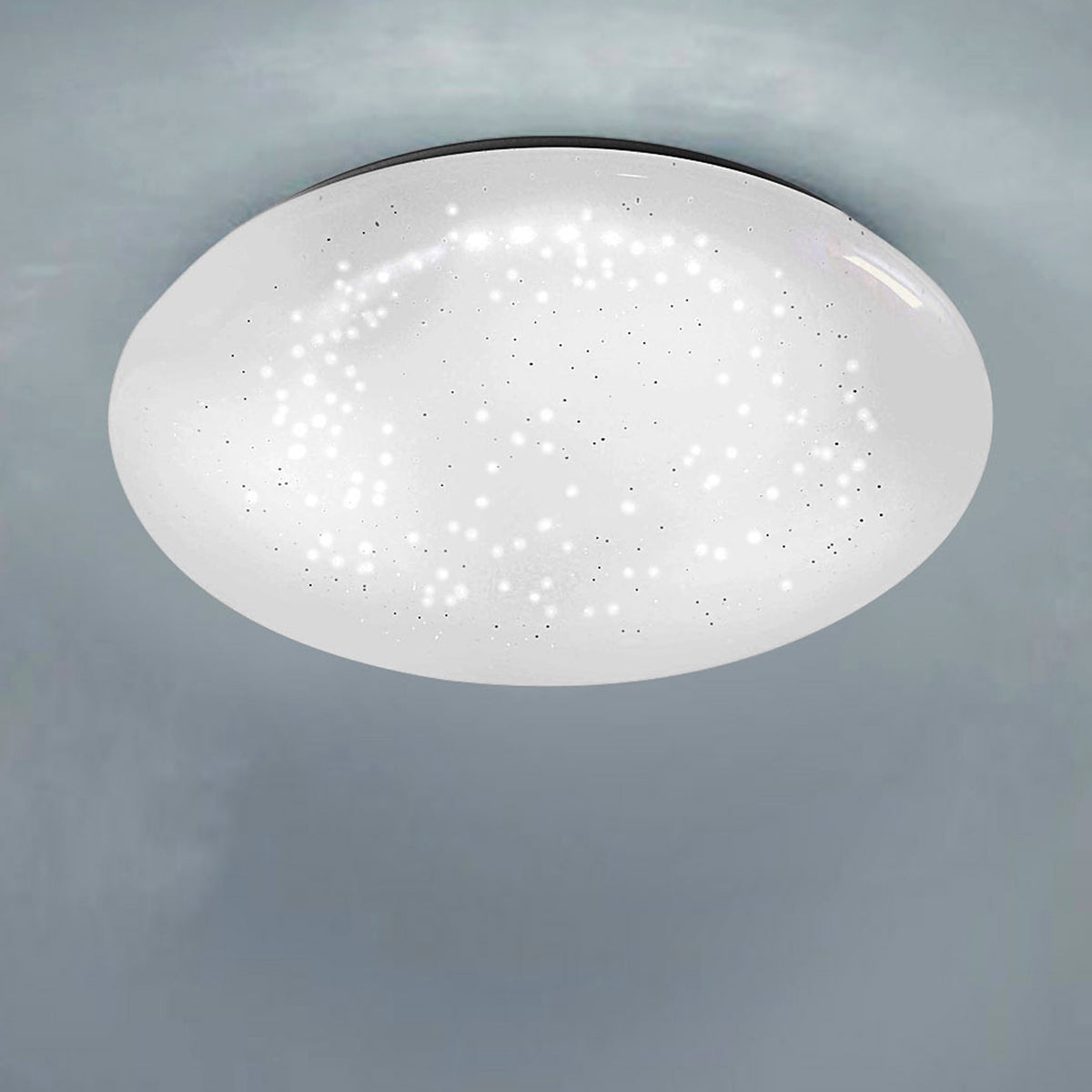 Vue rapprochée du plafonnier allumé, monté au plafond, diffusant une lumière étoilée.