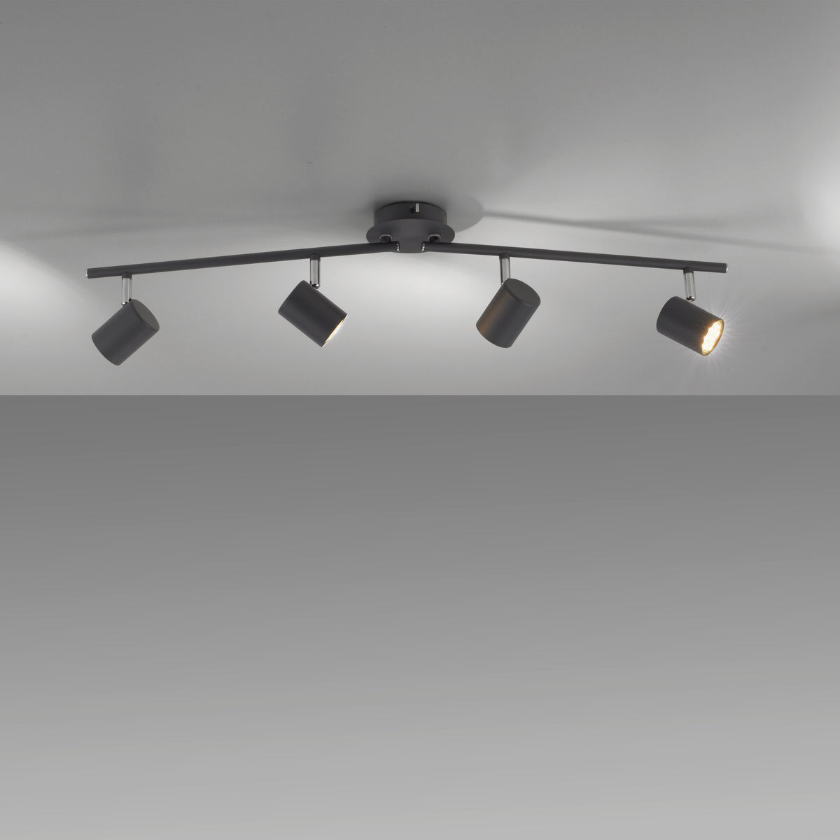 Luminaire allumé au plafond, quatre spots orientables créant des jeux d'ombres.