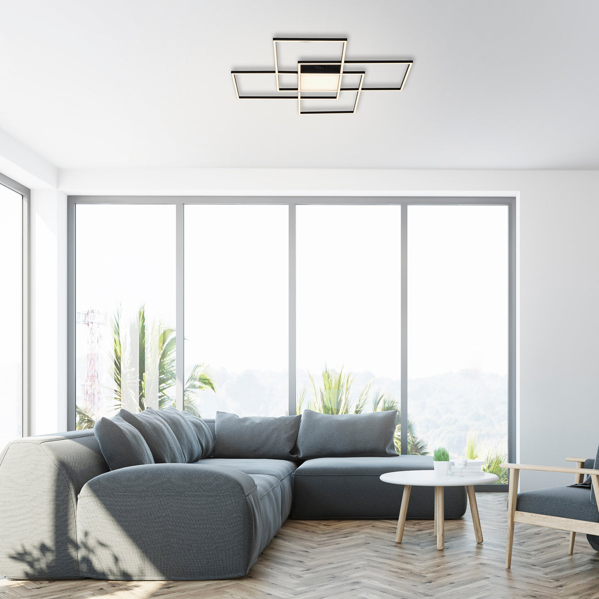 Mise en ambiance du plafonnier noir au plafond d'un salon moderne avec canapé gris.