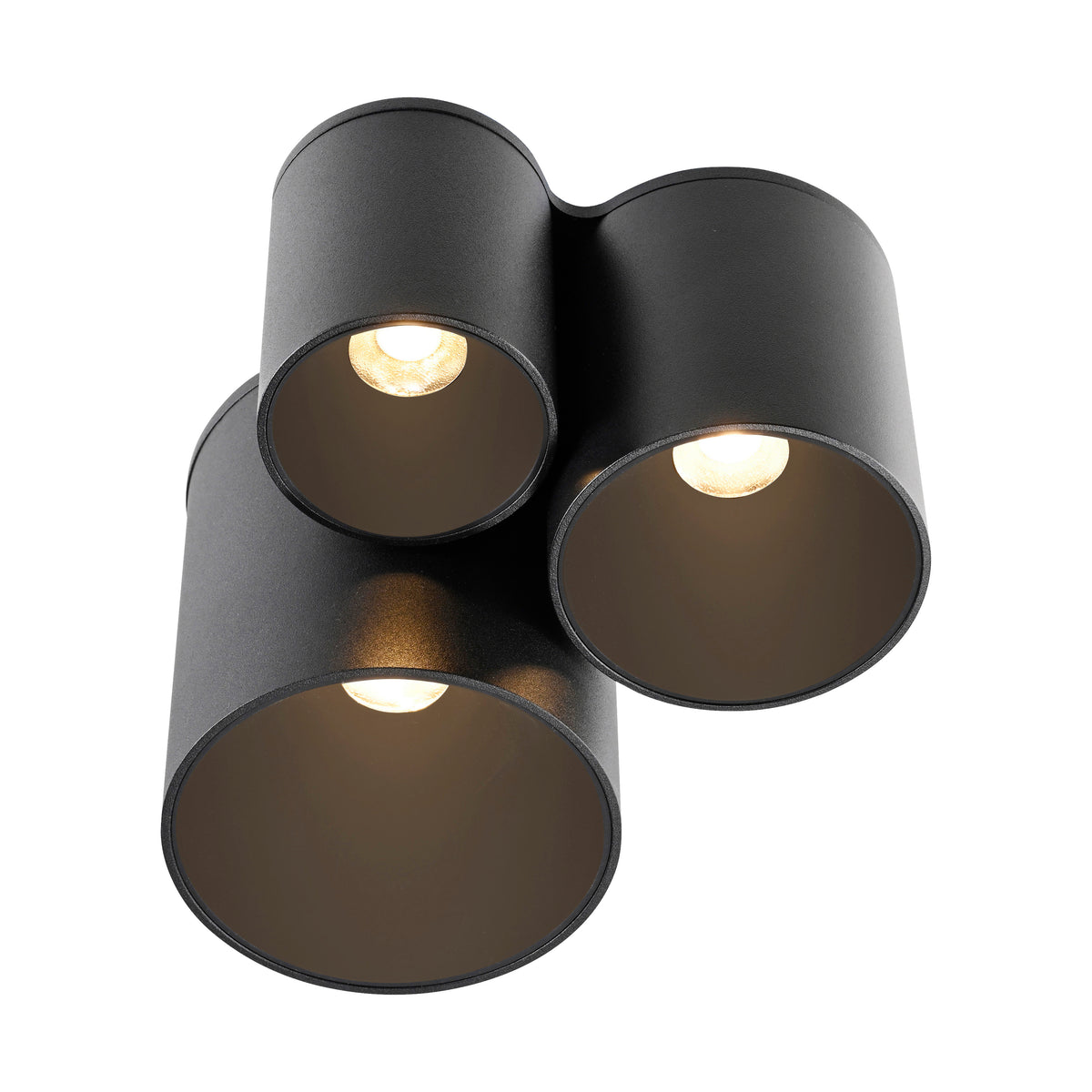 Vue rapprochée par-dessous, trois cylindres noirs allumés, intérieur doré réfléchissant la lumière.