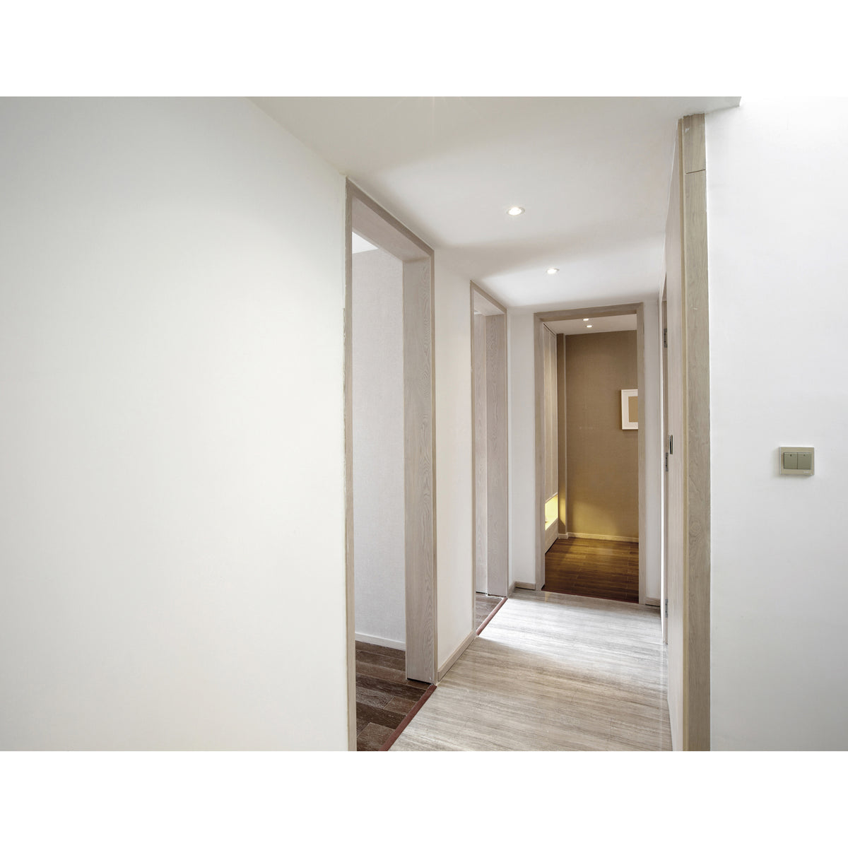 Couloir moderne éclairé par des spots encastrés au plafond et portes en bois clair