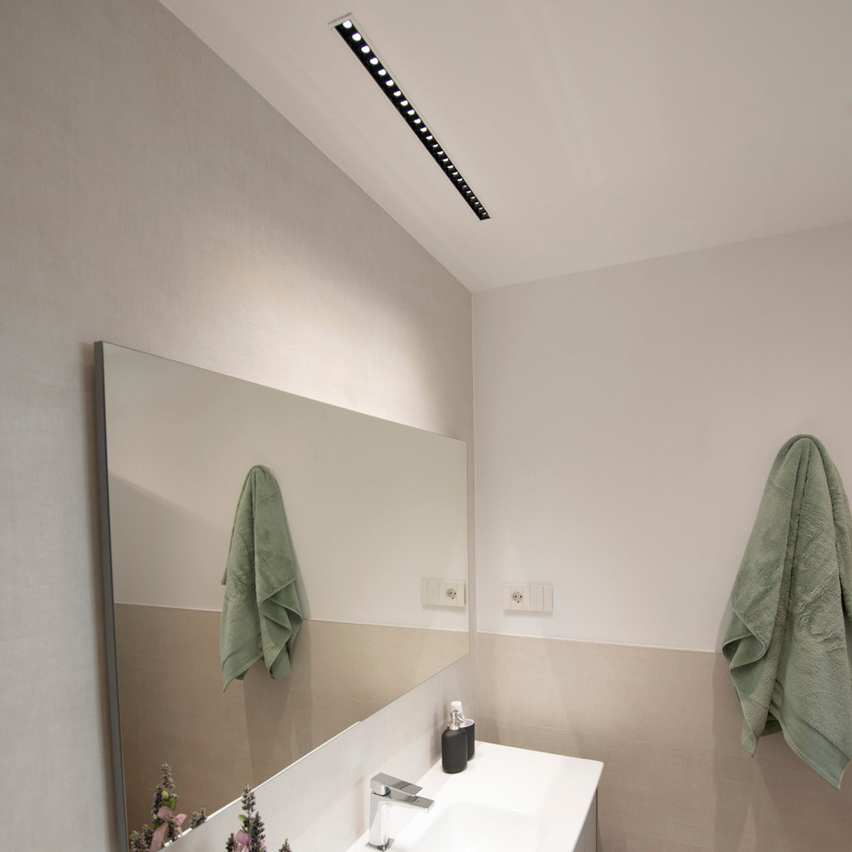 Luminaire encastré au plafond au-dessus d'un miroir dans une salle de bain.