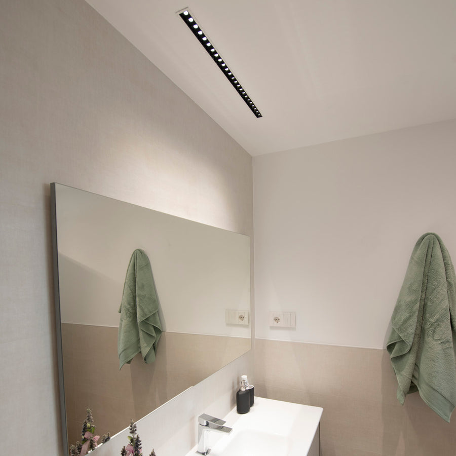 Luminaire encastré au plafond au-dessus d'un miroir dans une salle de bain.