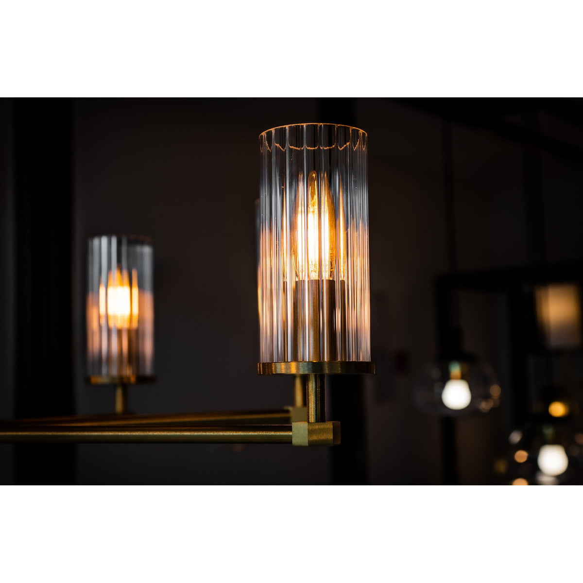 Gros plan sur un diffuseur cylindrique en verre strié éclairé, ampoule à filament bien visible
