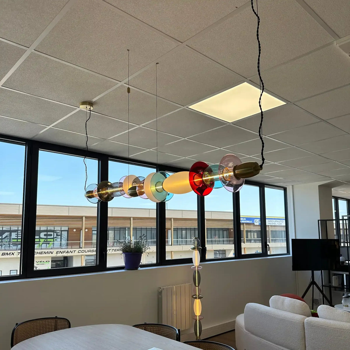 Vue en contre-plongée des suspensions colorées sous le plafond dallé et les fenêtres