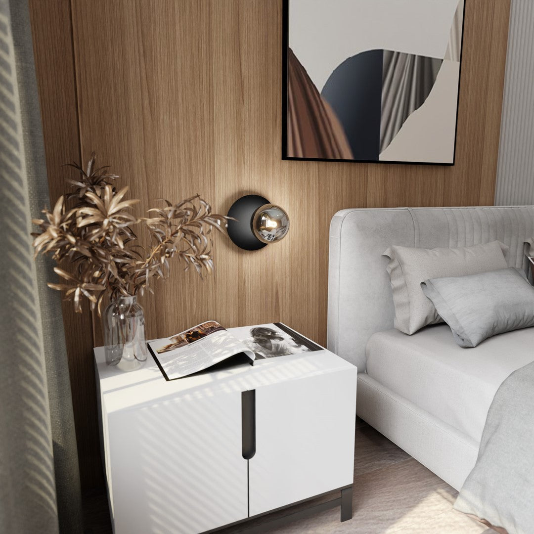 Mise en ambiance dans une chambre, applique allumée au-dessus de la table de nuit