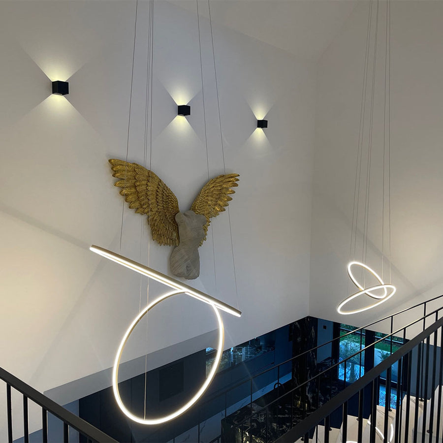 Anneaux dorés suspendus en hauteur devant décor mural d'ange doré