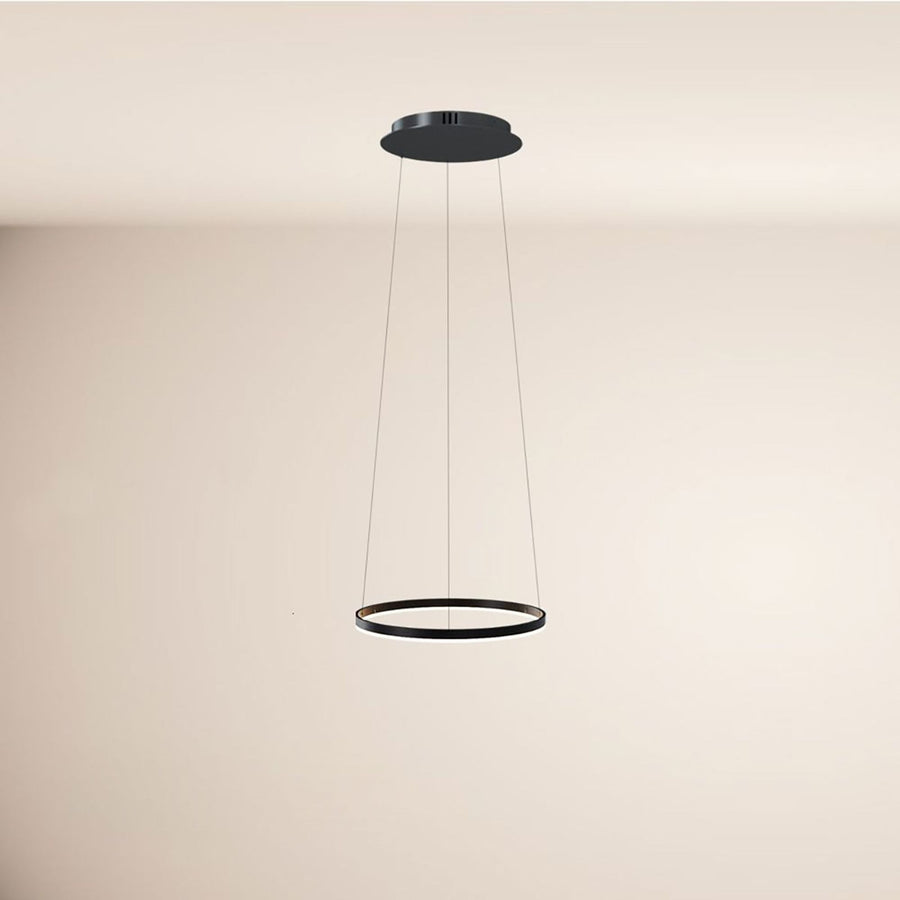 Suspension noire circulaire fine, suspendue par câbles devant un mur beige, vue de face.