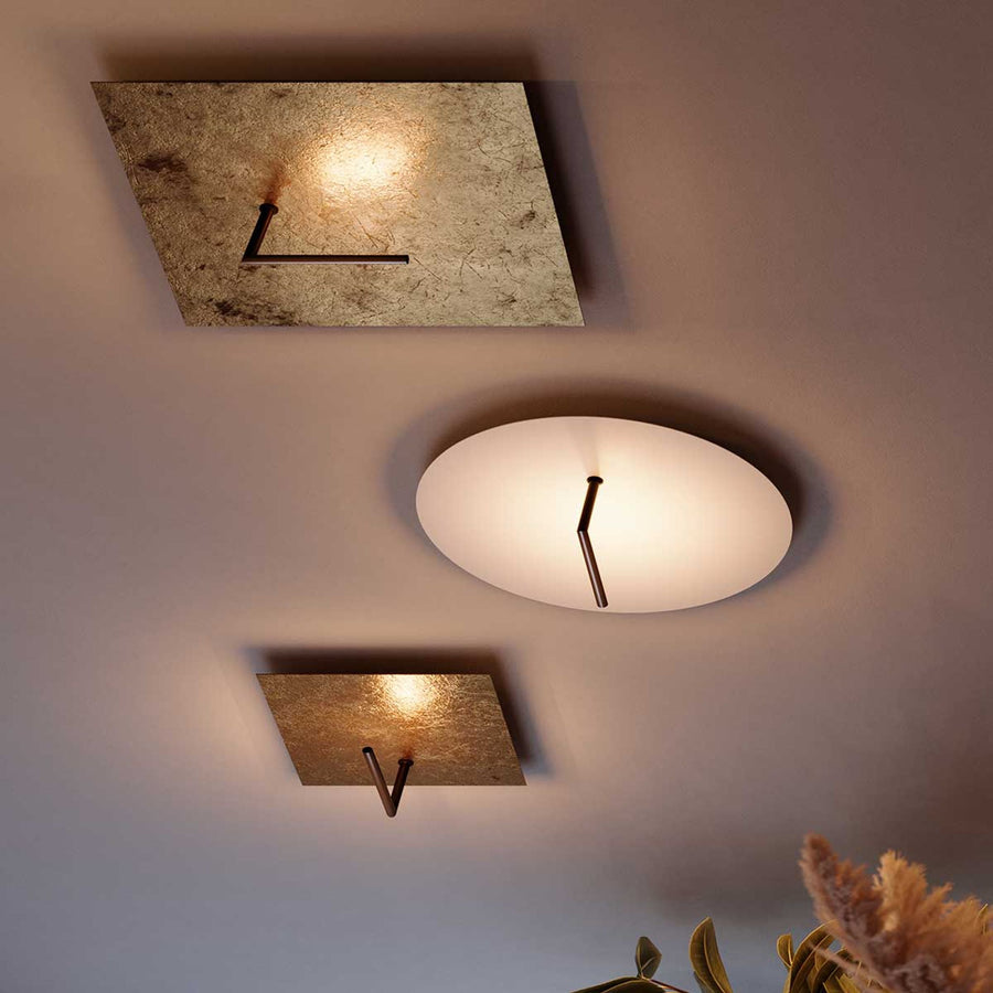 Trois luminaires plafonniers rectangulaires dorés et un ovale blanc fixés au plafond