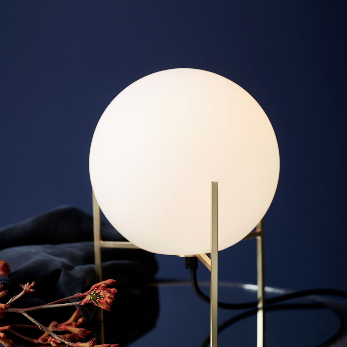 Gros plan sur la sphère lumineuse et le montant vertical en laiton.