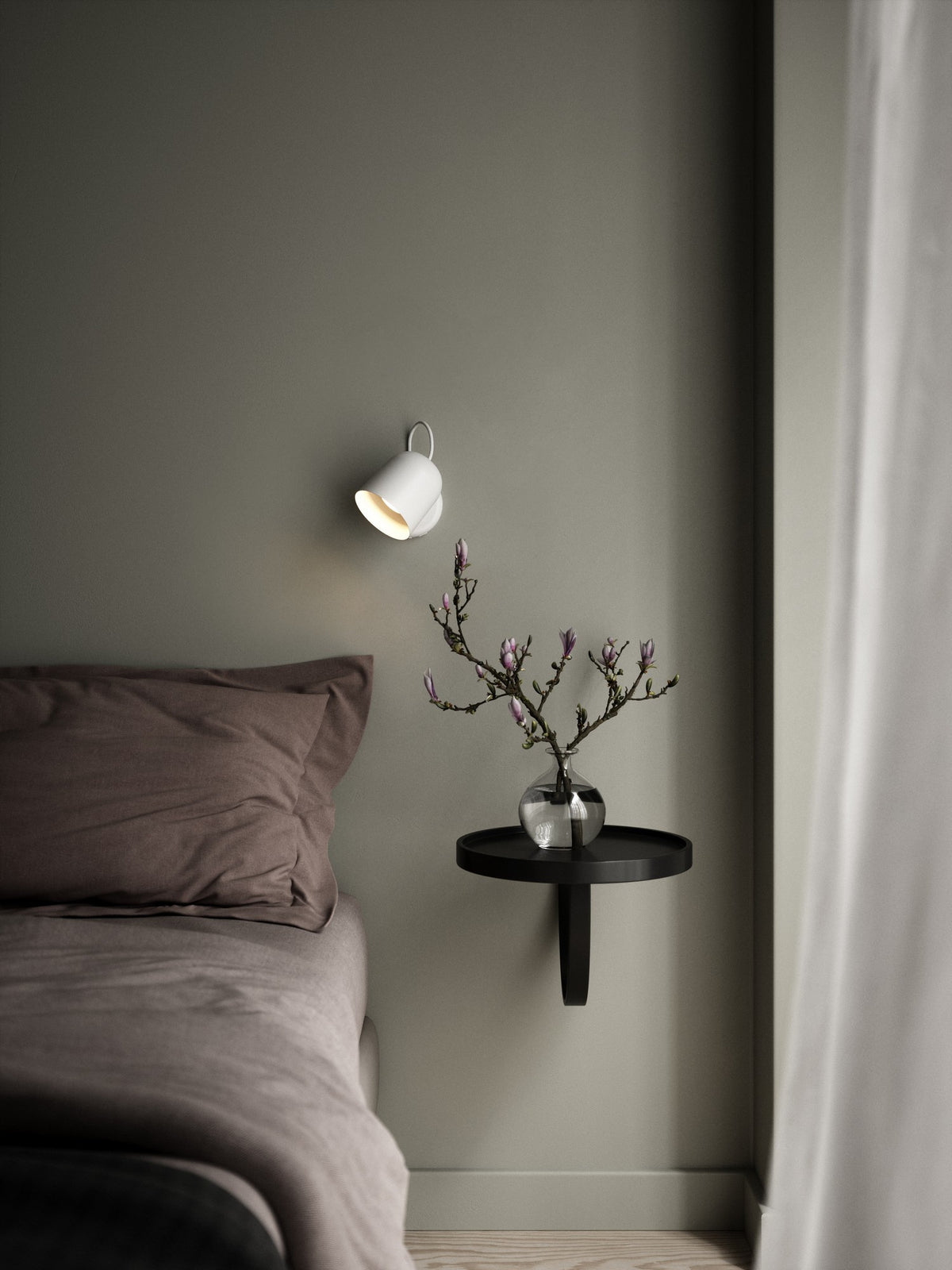 Mise en ambiance chambre avec applique murale blanche allumée au-dessus table de chevet.