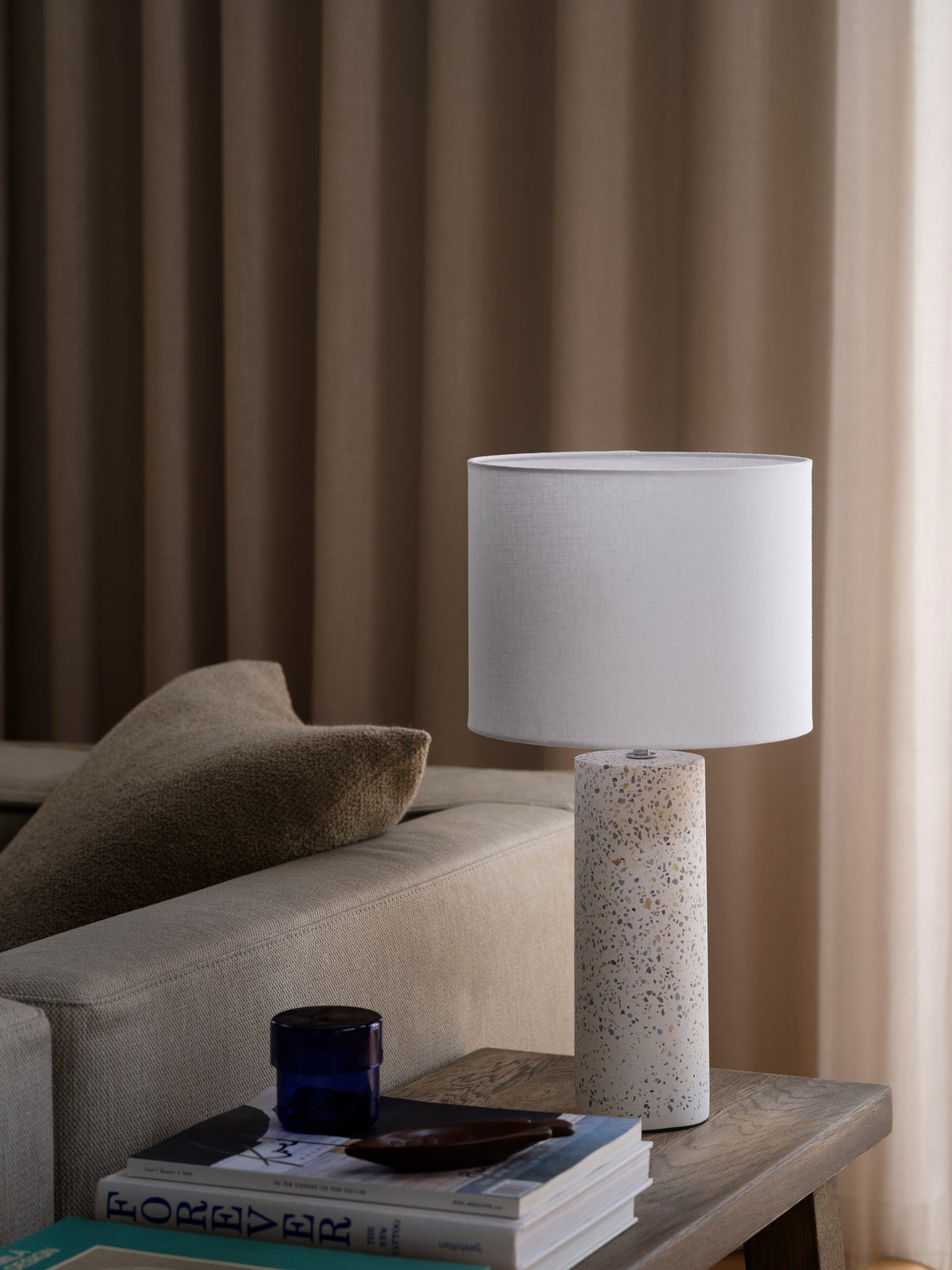 Lampe éteinte sur table en bois, canapé beige et coussin, ambiance intérieure contemporaine