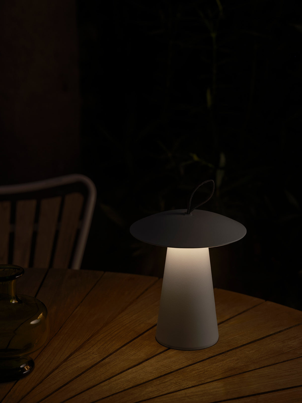 Lampe allumée posée sur une table en bois, ambiance nocturne et lumière chaude.