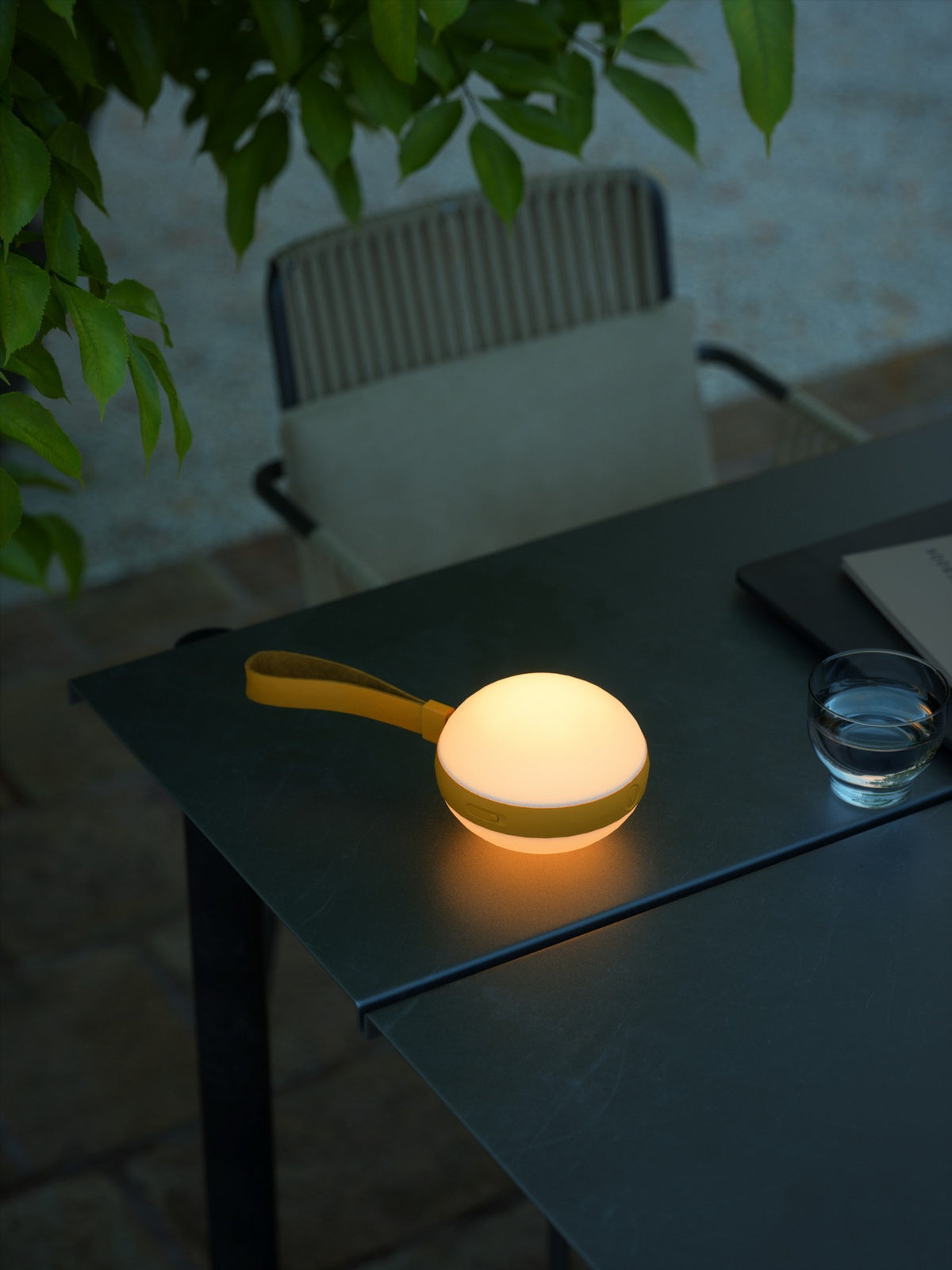 Lampe allumée posée sur une table sombre près d'un verre d'eau.
