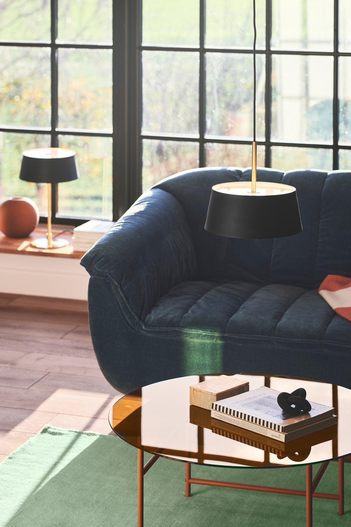 Mise en ambiance dans un salon, canapé bleu et grande baie vitrée