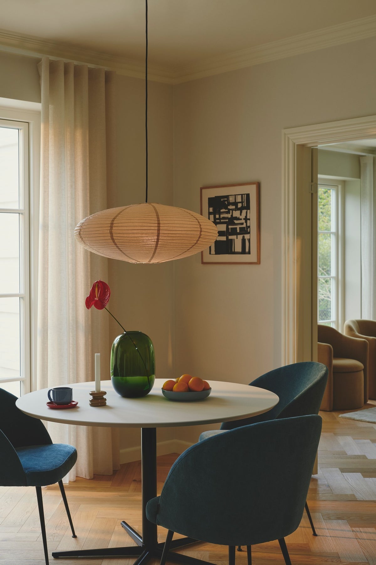 Même suspension ovale allumée avec cordon noir, dans une salle à manger moderne.