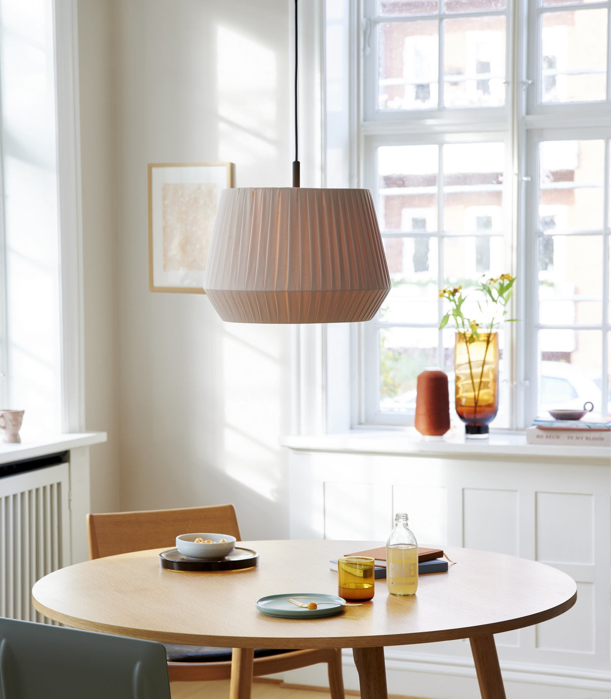 Mise en ambiance au-dessus d'une table ronde en bois dans une salle à manger lumineuse.