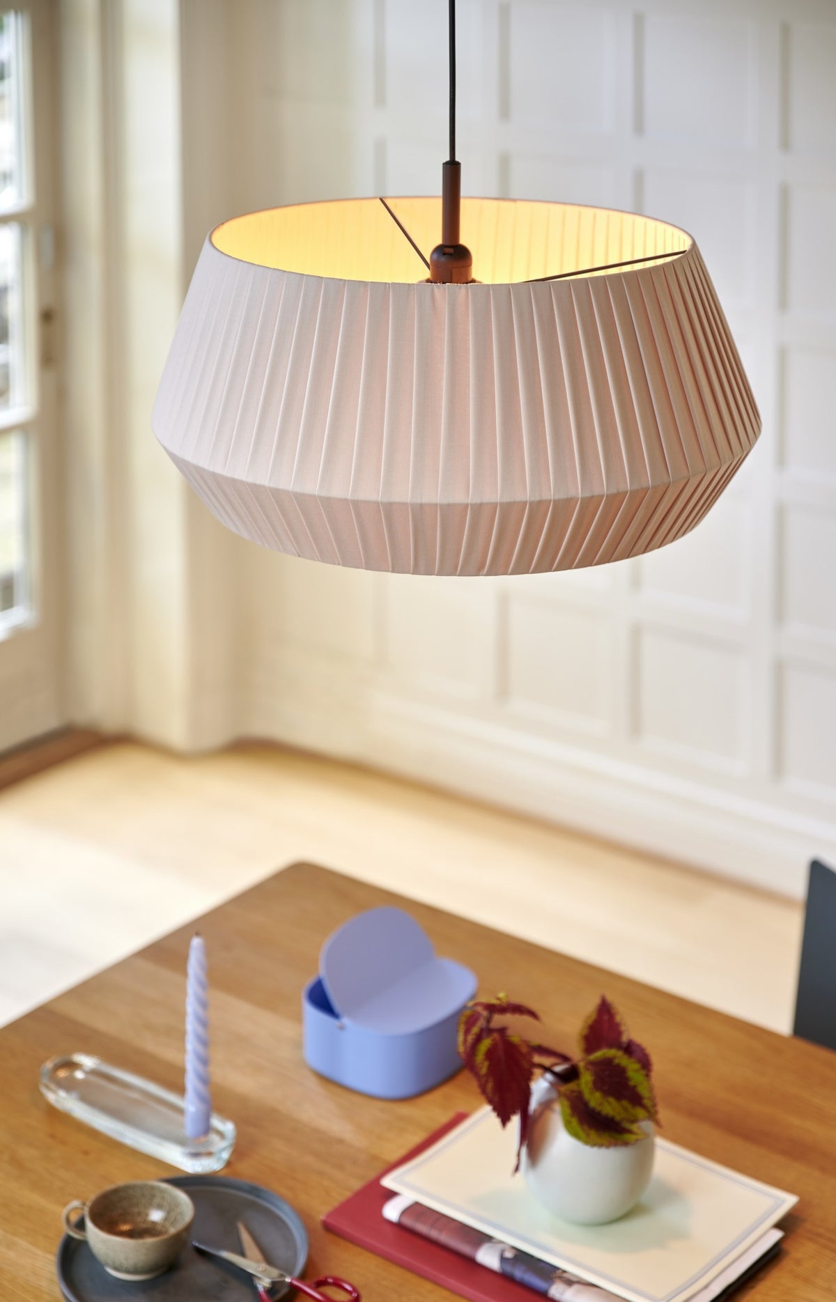 Mise en ambiance : suspension allumée au-dessus d'une table en bois décorée